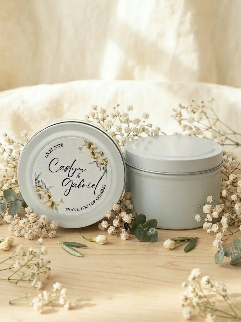 Two white containers with decorative labels on a wooden surface with baby's breath flowers.